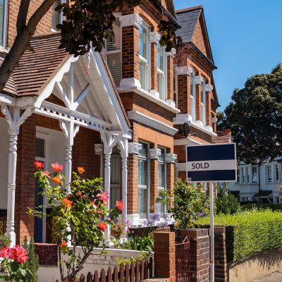 House Sold sign on attractive street of residential British hous